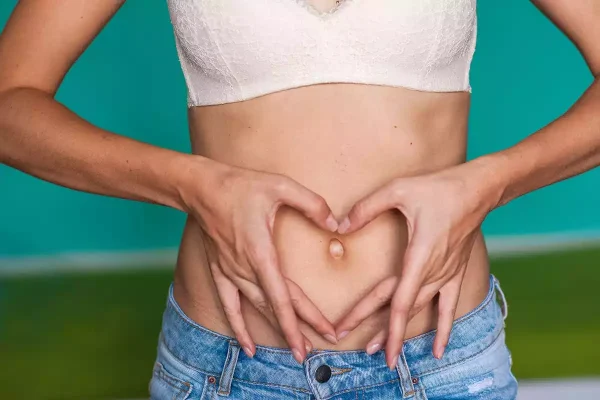 Mulher com as mãos sobre a barriga representando o cuidado ao aplicar injeção na barriga durante a FIV.