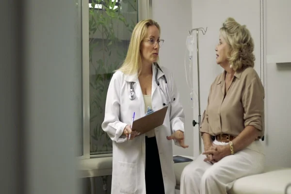 Médica conversando com mulher de meia idade representando dúvida se a FIV pode ser feita na menopausa.