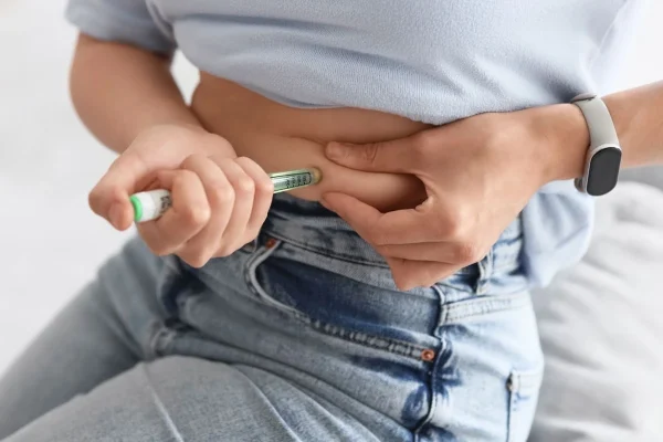 Mulher aplicando medicação hormonal representando bloqueadores de ovulação precoce no tratamento de fertilidade.