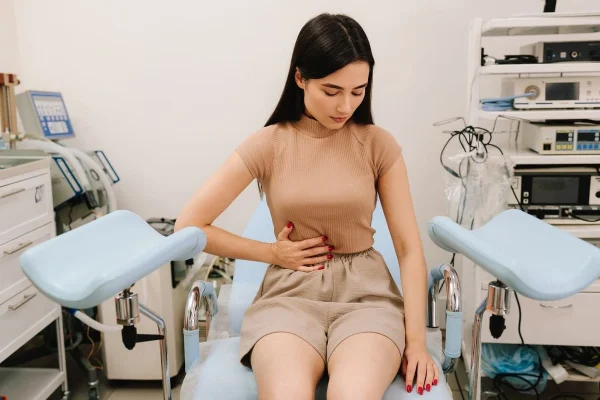 Mulher com desconforto abdominal ilustrando disfunções ovulatórias.