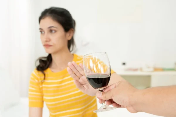 Mulher recusando taça de vinho representando o que evitar durante indução hormonal para a FIV.