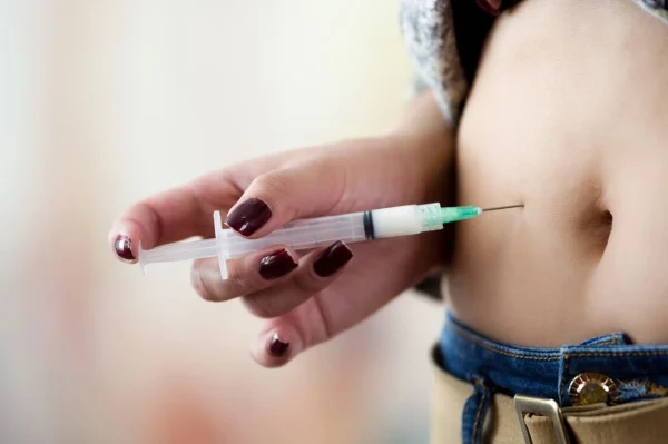 Mulher aplicando injeção hormonal na barriga ilustrando o uso de Lupron na FIV.