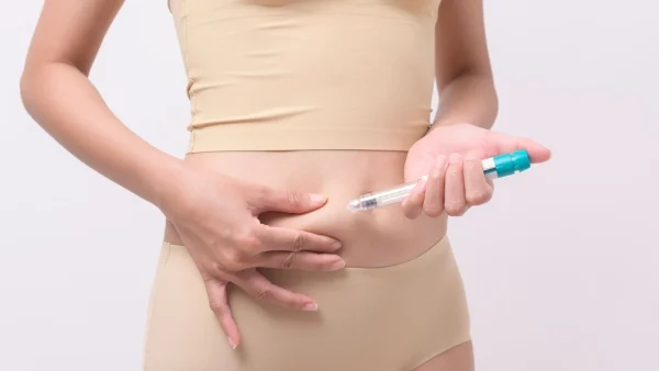 Um mulher aplicando o estimulante de óvulos em sua barriga.